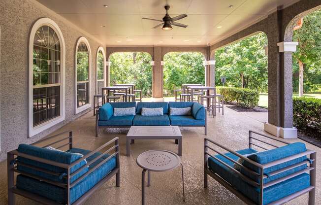 a covered patio with couches tables and chairs and a ceiling fan