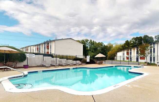 A large outdoor swimming pool with a white fence surrounding it.