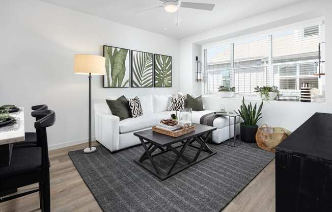 Living Room with Wood-Style Flooring, Area Rug, Sectional Couch, Coffee Table, Cabinet, TV, Ceiling Fan, Patio Door, and Large Window with Blinds at Solstice at Fiddyment Ranch, Roseville, CA, 95747