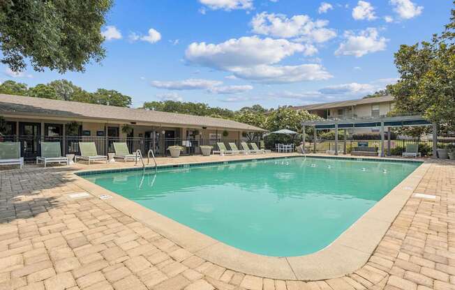 A large outdoor swimming pool surrounded by a brick patio.