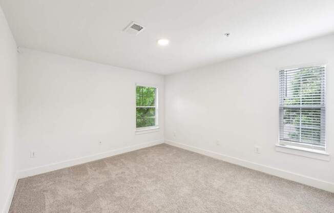 A bed room with a carpeted floor and a windows with blinds.