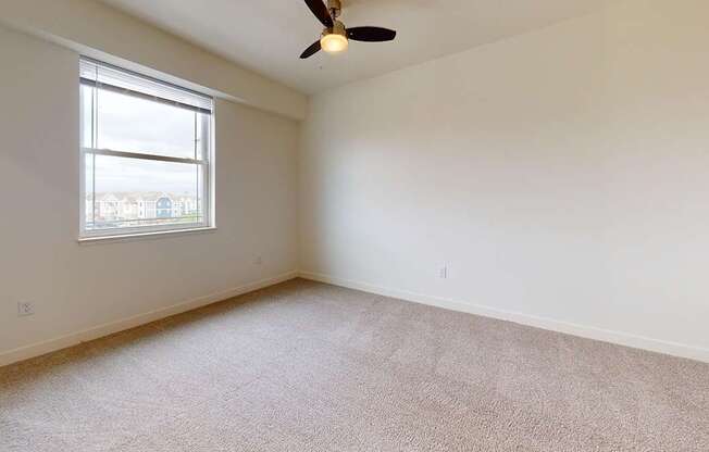 A bedroom with a ceiling fan and a window at The Reserve at Destination Pointe apartments, Grimes, IA