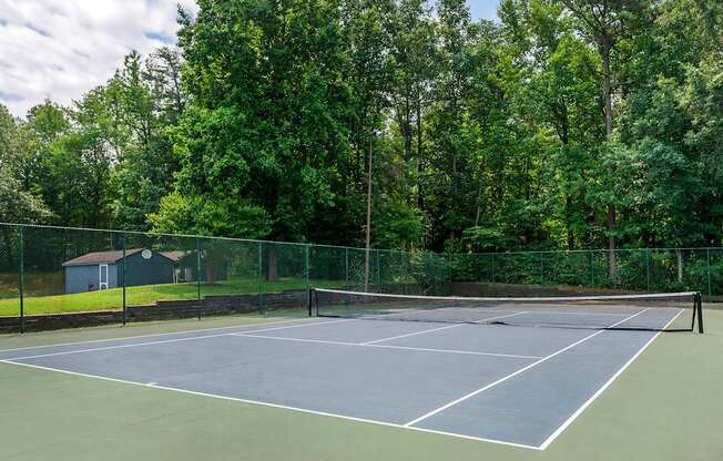 a tennis court with a house and trees in the background