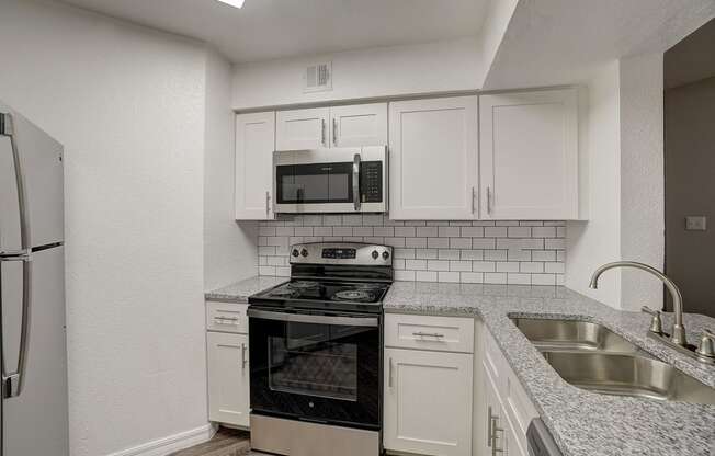 an empty kitchen with white cabinets and black appliances