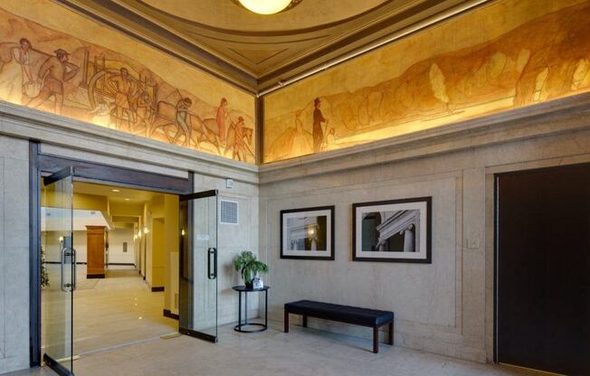 the lobby of a building with paintings on the wall and a bench