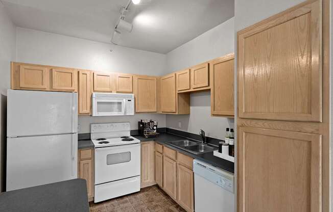 A kitchen with oak cabinets, white appliances, track lighting and a kitchen island with storage.