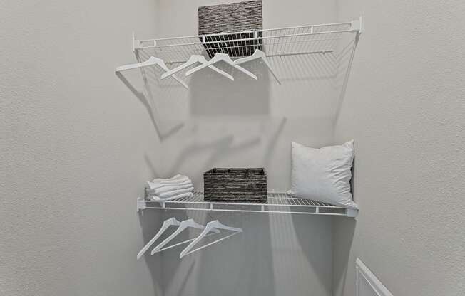 A white closet with clothes hanging on hangers.