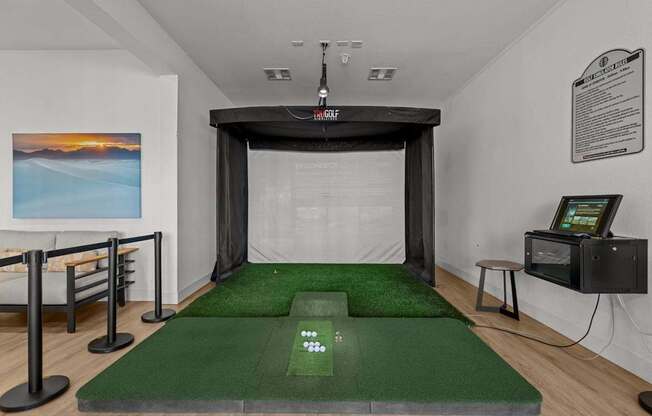 A room with a green carpet and a white wall with a painting on it.