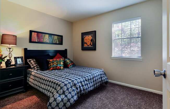 A bedroom with a bed, dresser, and window.