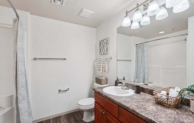 A bathroom with a toilet, sink, and mirror.