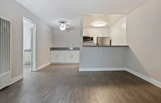 an empty living room and kitchen with wood flooring