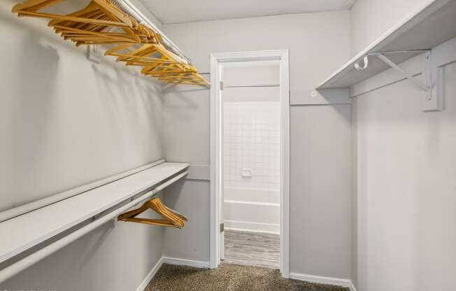 a walk in closet with white walls and white closet doors and a white closet door