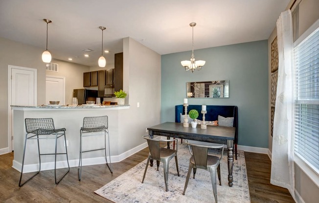 Kitchen with small dining room space. Breakfast bar with stools. Dining area with a table couch and two chairs at at Ascent at Mallard Creek Charlotte, NC