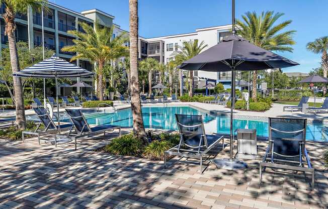 a swimming pool with blue chairs and umbrellas next to a hotel pool