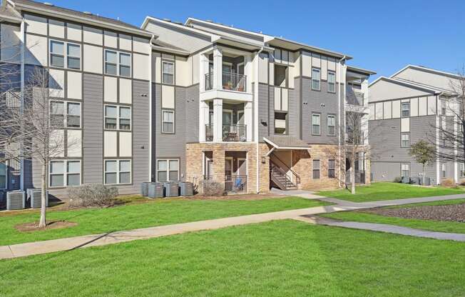 an exterior view of an apartment building with green grass and sidewalks