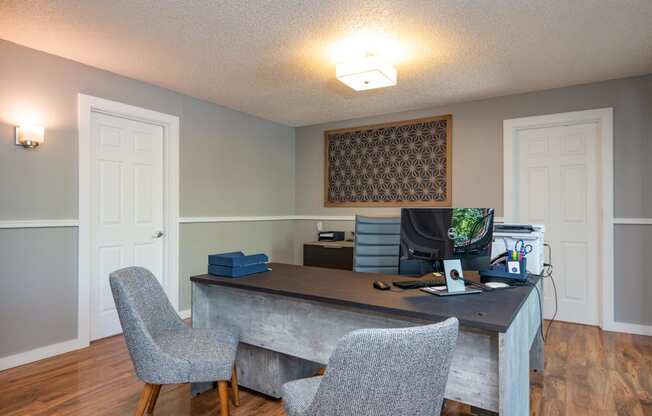 grey desk with two grey chairs in front.