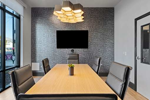 a conference room with a table and chairs and a television on the wall at SevenO2 Main Apartments, Salt Lake City