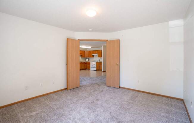 A room with a carpeted floor and a doorway leading to another room. Fargo, ND Stonebridge Apartments
