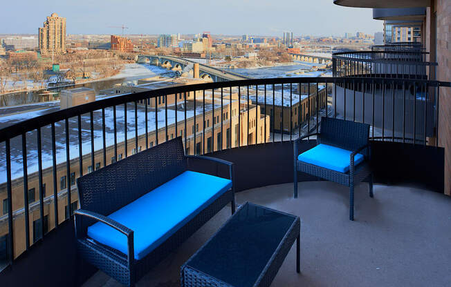 A balcony with a black railing has two chairs and a table.