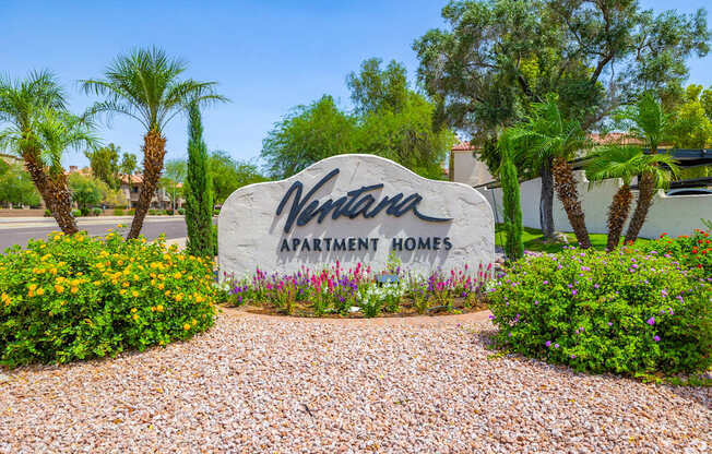 A sign that says "Verna Apartment Homes" in front of some trees and bushes.
