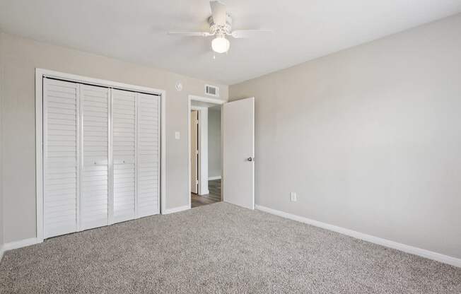 A room with a ceiling fan and carpeted floor.