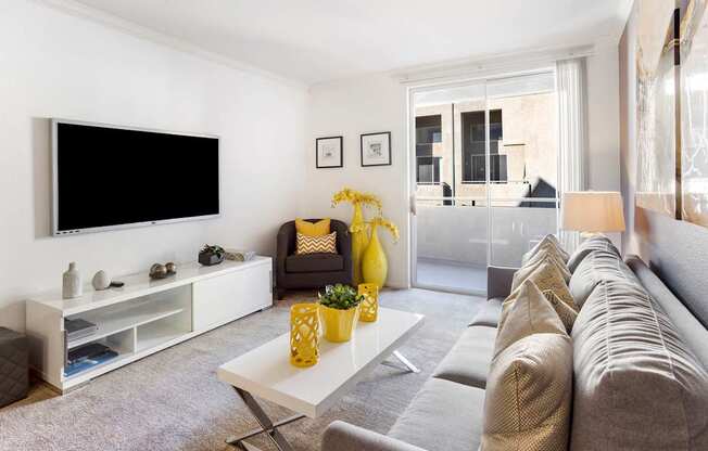 A living room with a grey couch, a white coffee table, and a black television.