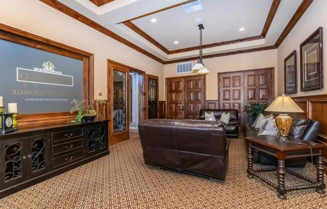 A cozy, elegantly decorated waiting area featuring a dark leather sofa, wooden furniture, and a decorative lamp. Rich brown wood paneling and a patterned carpet complement the warm ambiance. The wall displays an ornate sign, and doors in the background add to the room's inviting and professional atmosphere.