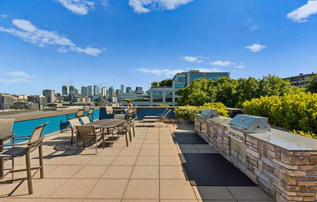 an outdoor terrace with tables and chairs and a pool with a cityscape in the background at Dexter Lake Union, Seattle