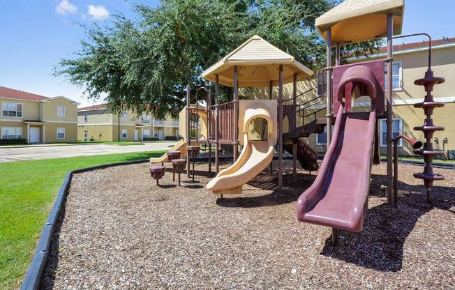 A playground with a red slide and a yellow canopy.