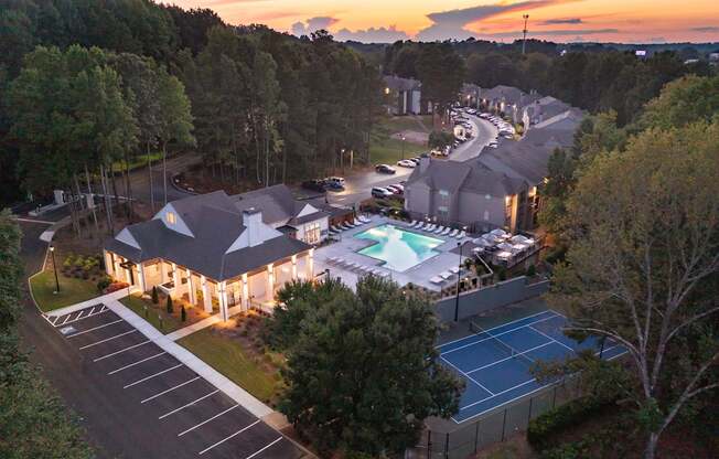 A sunset view of a residential area with a tennis court and pool.