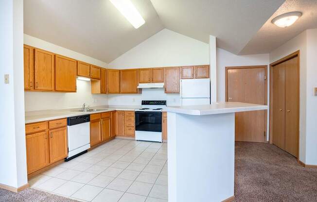 A kitchen with wooden cabinets and white appliances. Fargo, ND Summit Point Apartments