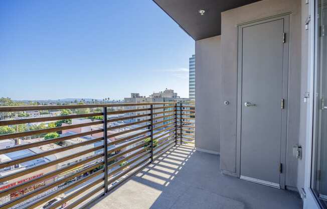the view of the city from the balcony of an apartment with a door and rail