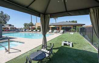 A pool area with a table and chairs under a canopy.