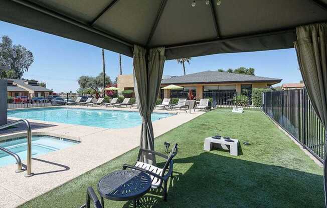 A pool area with a table and chairs under a canopy.