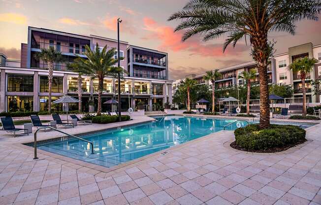 a swimming pool in front of a building with palm trees