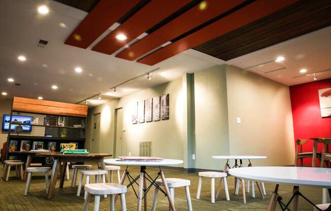 a dining area with tables and stools and a bar in the background