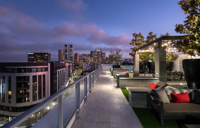 A landscaped rooftop entertaining area with a city skyline view and multiple dining and seating areas.