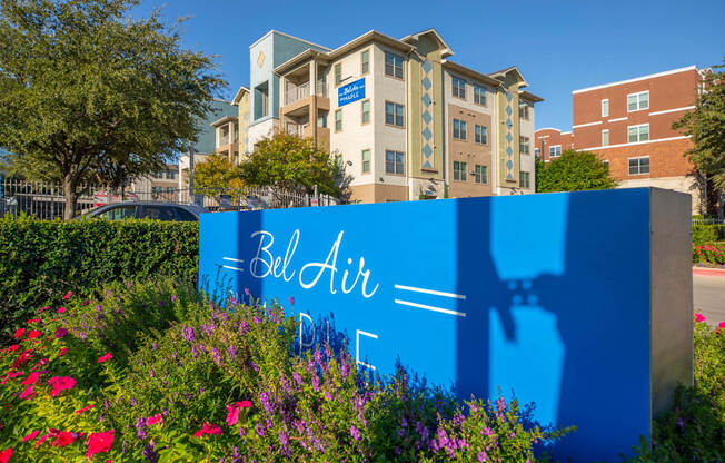 A blue sign with the words "Bell Air" on it in front of a building.