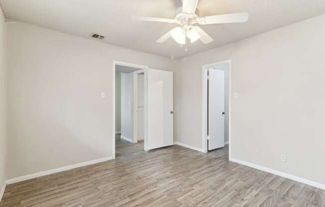 a spacious bedroom with white walls and a ceiling fan