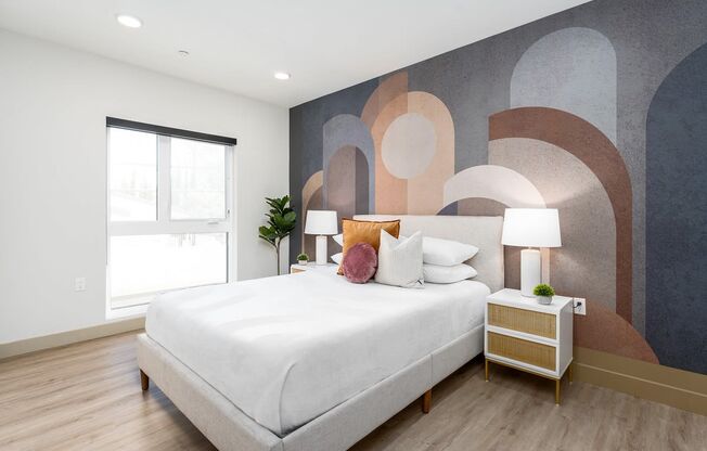 a bedroom with a large white bed and a wall with a geometric design