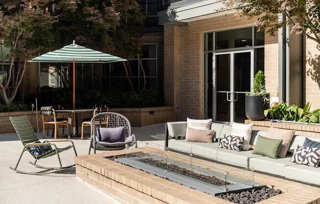 A patio with a couch, chairs, and an umbrella.