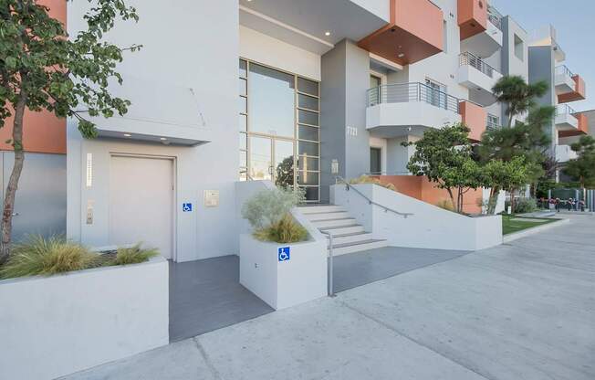 A modern building with a white and orange exterior and a tree in front at Woodley Sara Apartment, Van Nuys, 91406