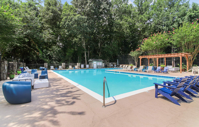 A large swimming pool surrounded by trees and lounge chairs.