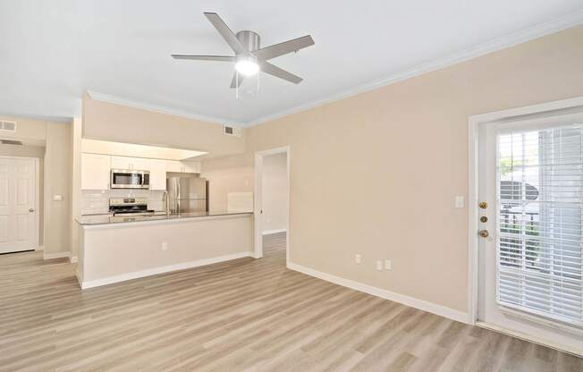 a living room with a kitchen and a ceiling fan