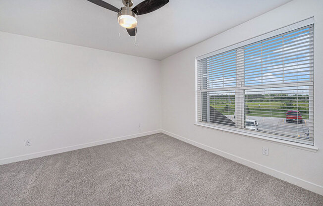 bedroom with a large window and a ceiling fan at Trade Winds Apartment Homes, Elkhorn, Nebraska