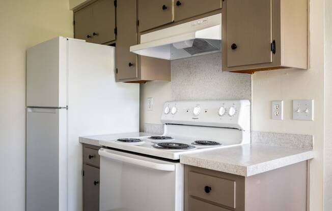 an empty kitchen with white appliances and a refrigerator