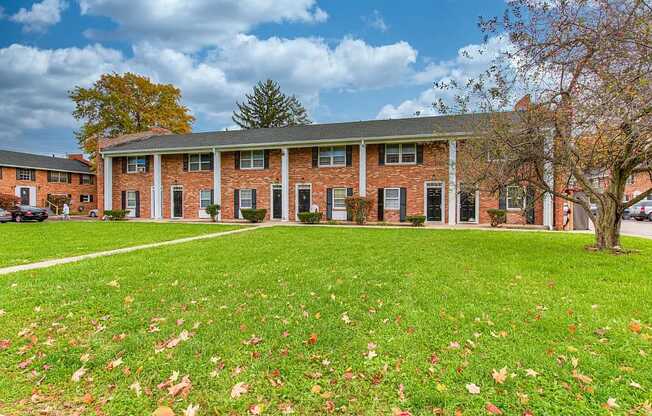 a large brick building with a green lawn in front of it