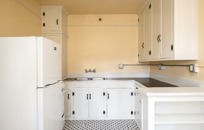 a kitchen with white cabinets and a black and white tile floor