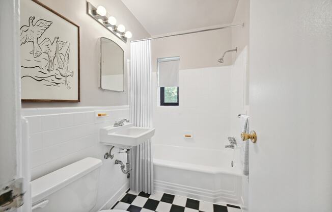 a white bathroom with a black and white checkered floor