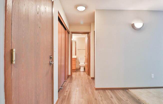 A long hallway with wooden floors and doors on either side.